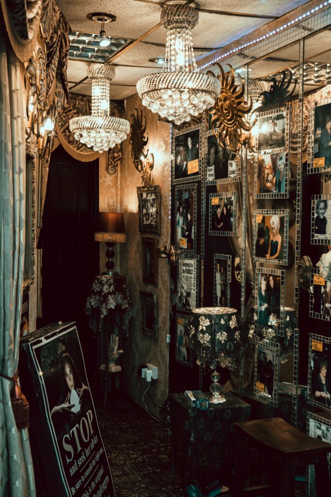 Crystal chandeliers hang from a ceiling, lighting a wall of photos.