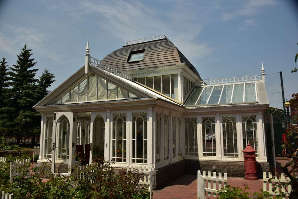 A white solarium with a brown/green room. Lots of windows and old fashioned looking.